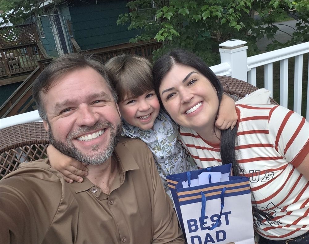 Isac smiling with his family on a porch